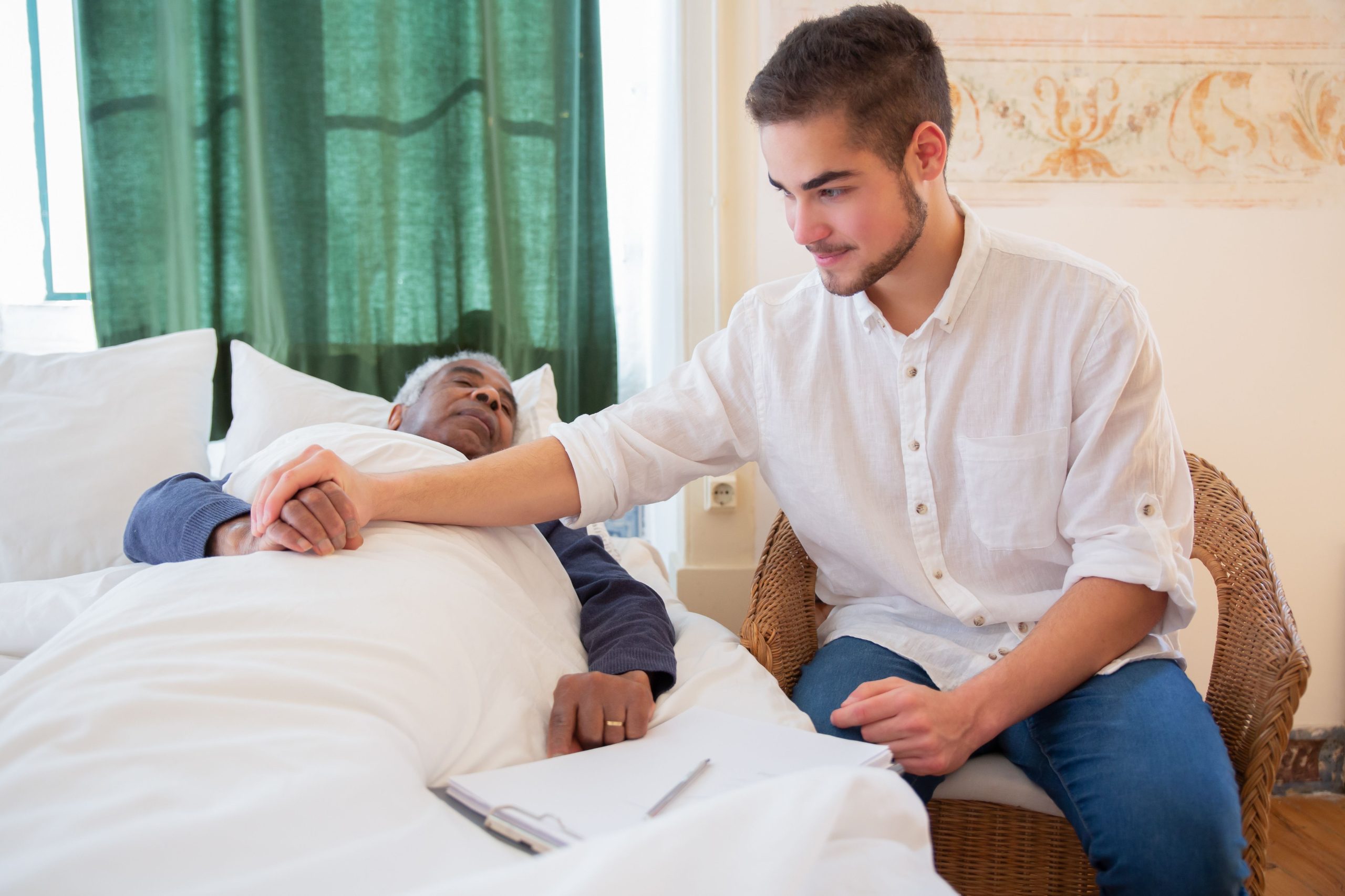 A young man comforts an elderly man in bed, foster warmth and care.